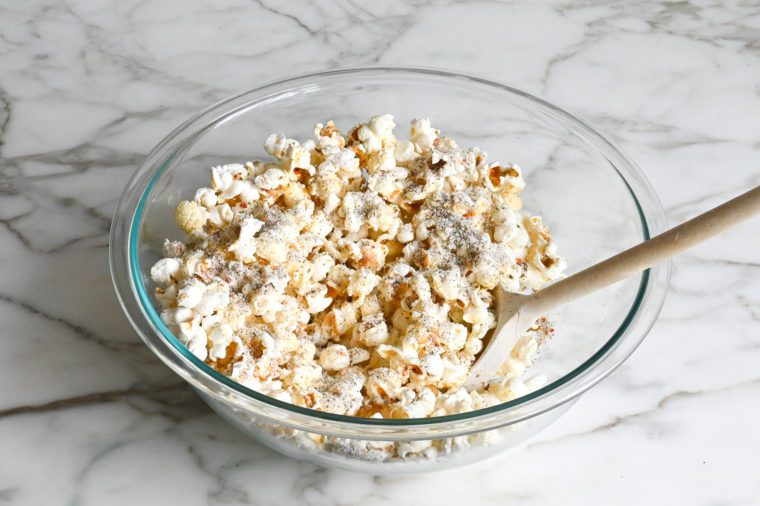 tossing the popcorn with the garlic butter and cheese mixture
