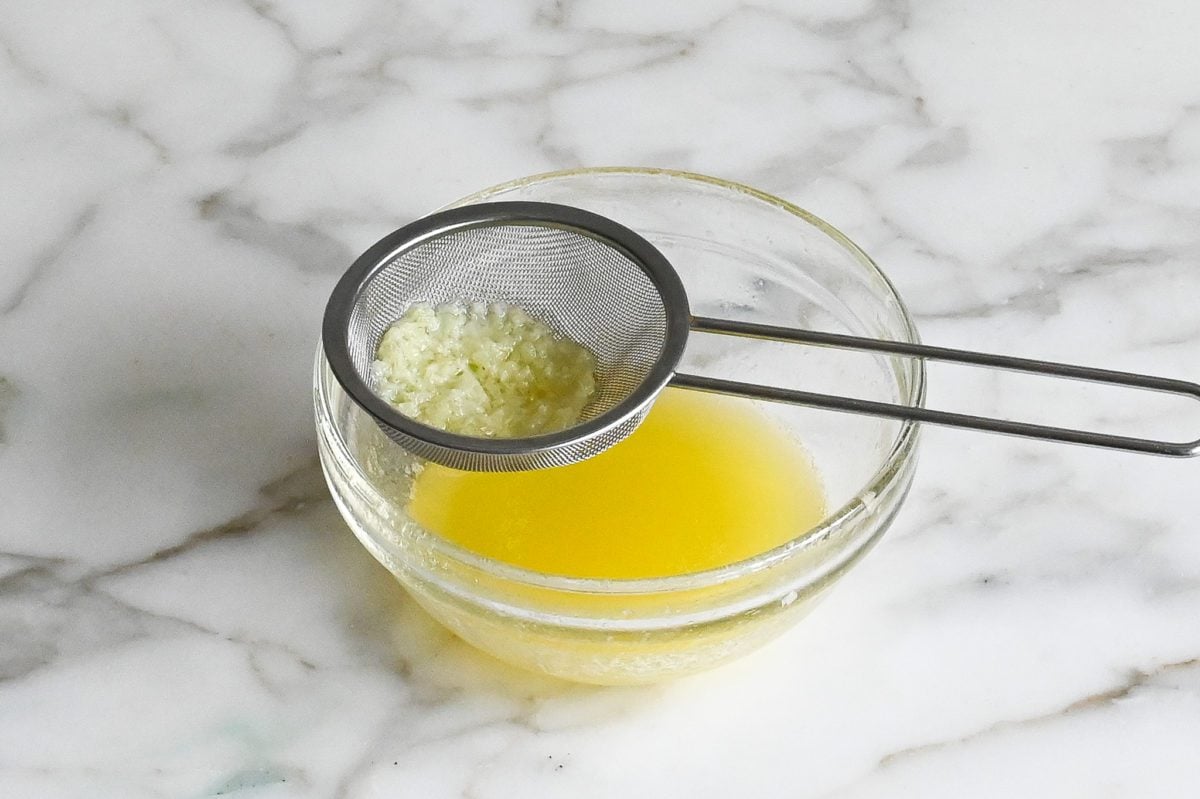 Sieve straining garlic.