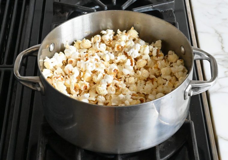 Pot of popped popcorn on a stovetop.