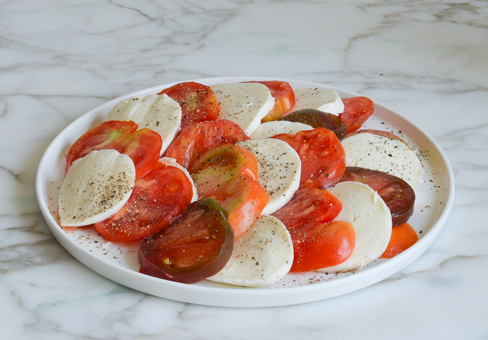 arranging the tomato slices and mozzarella on a platter