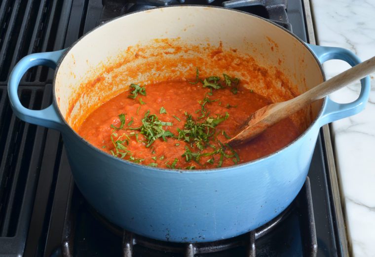 adding the basil to the tomato sauce