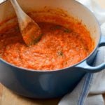 Wooden spoon in a Dutch oven of homemade tomato sauce.