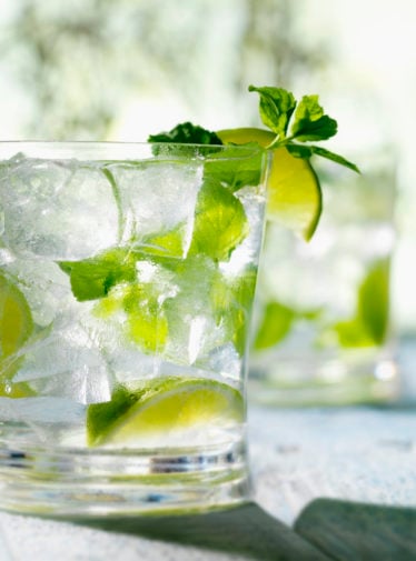 Mojito in a glass with ice, limes, and mint.