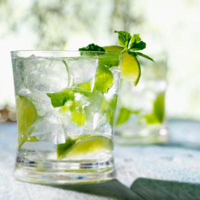 Mojito in a glass with ice, limes, and mint.