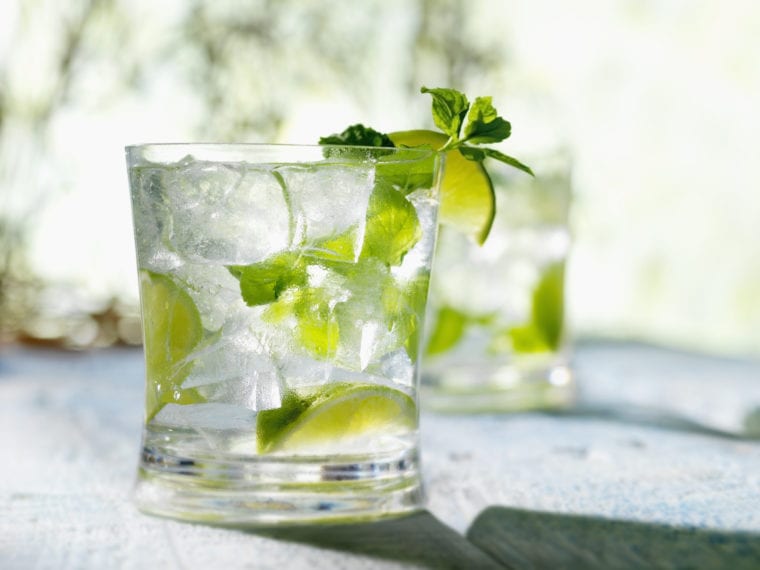 Mojito in a glass with ice, limes, and mint.