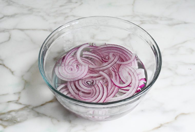 Sliced red onions in a bowl of water.