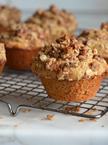 Oat muffins with pecan streusel topping on a wire rack.