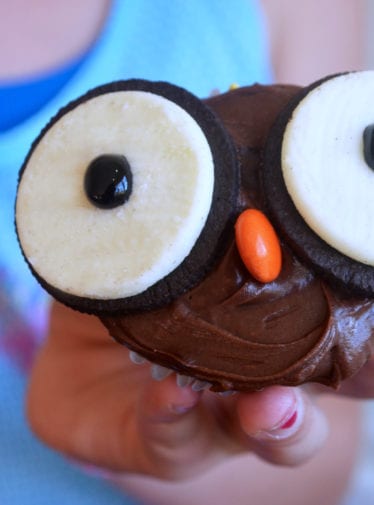 Girl holding a cupcake decorated like an owl.