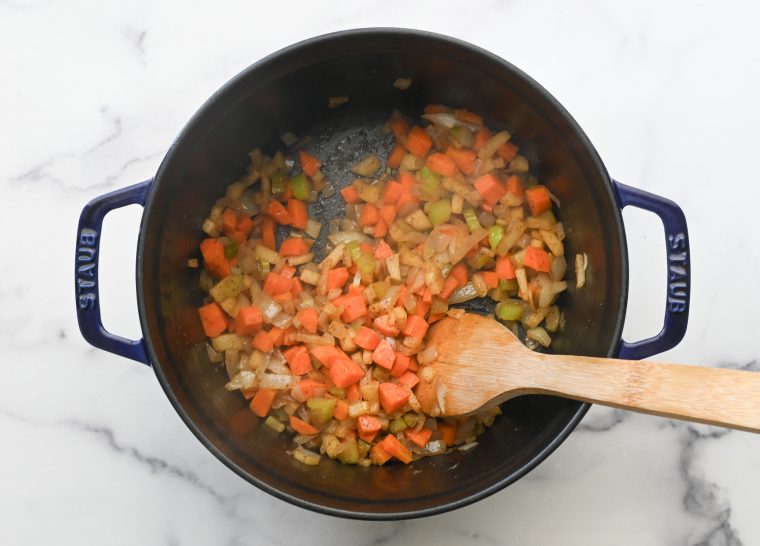 softened vegetables in pot with wooden spoon