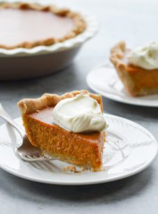 Slice of pumpkin pie on a plate with a fork.