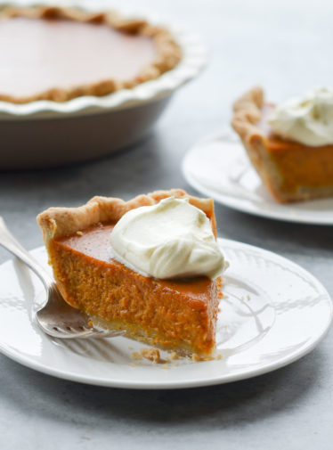 Slice of pumpkin pie on a plate with a fork.