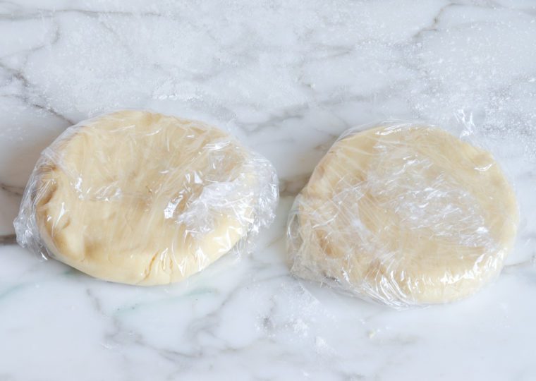 cut out sugar cookie dough discs in plastic wrap