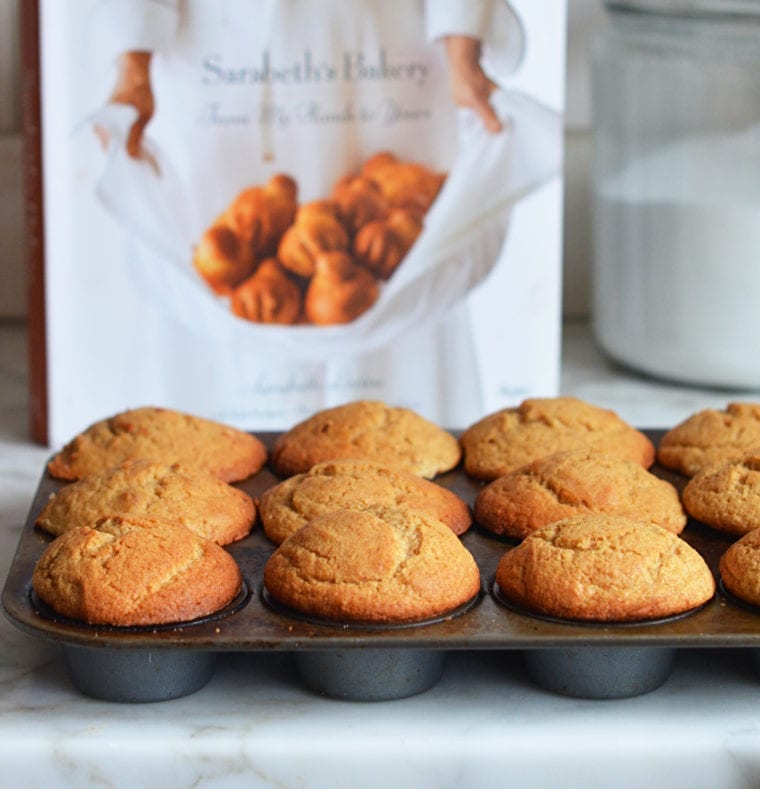 Muffin tin of maple muffins in front of a cookbook.