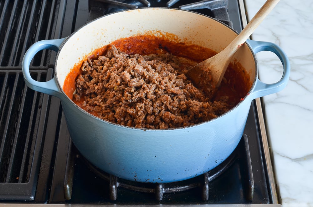 adding sausage to the lasagna sauce