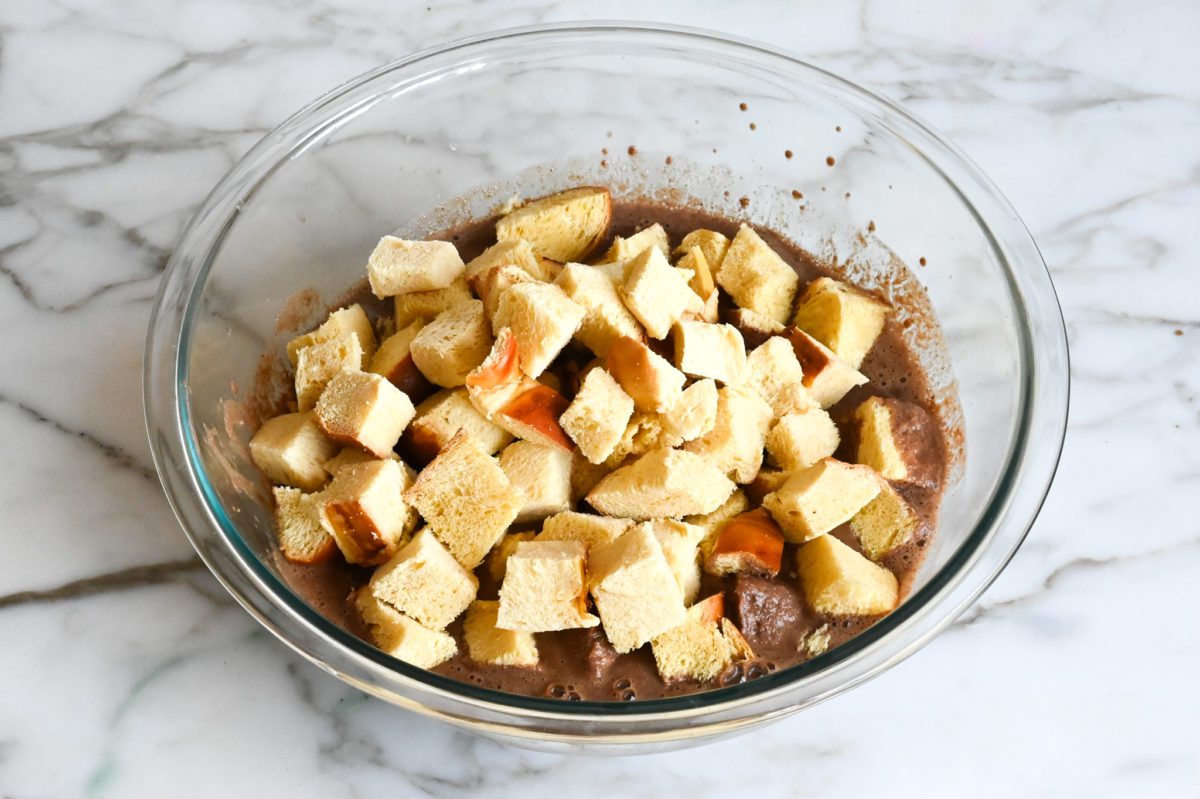 adding challah cubes to custard mixture