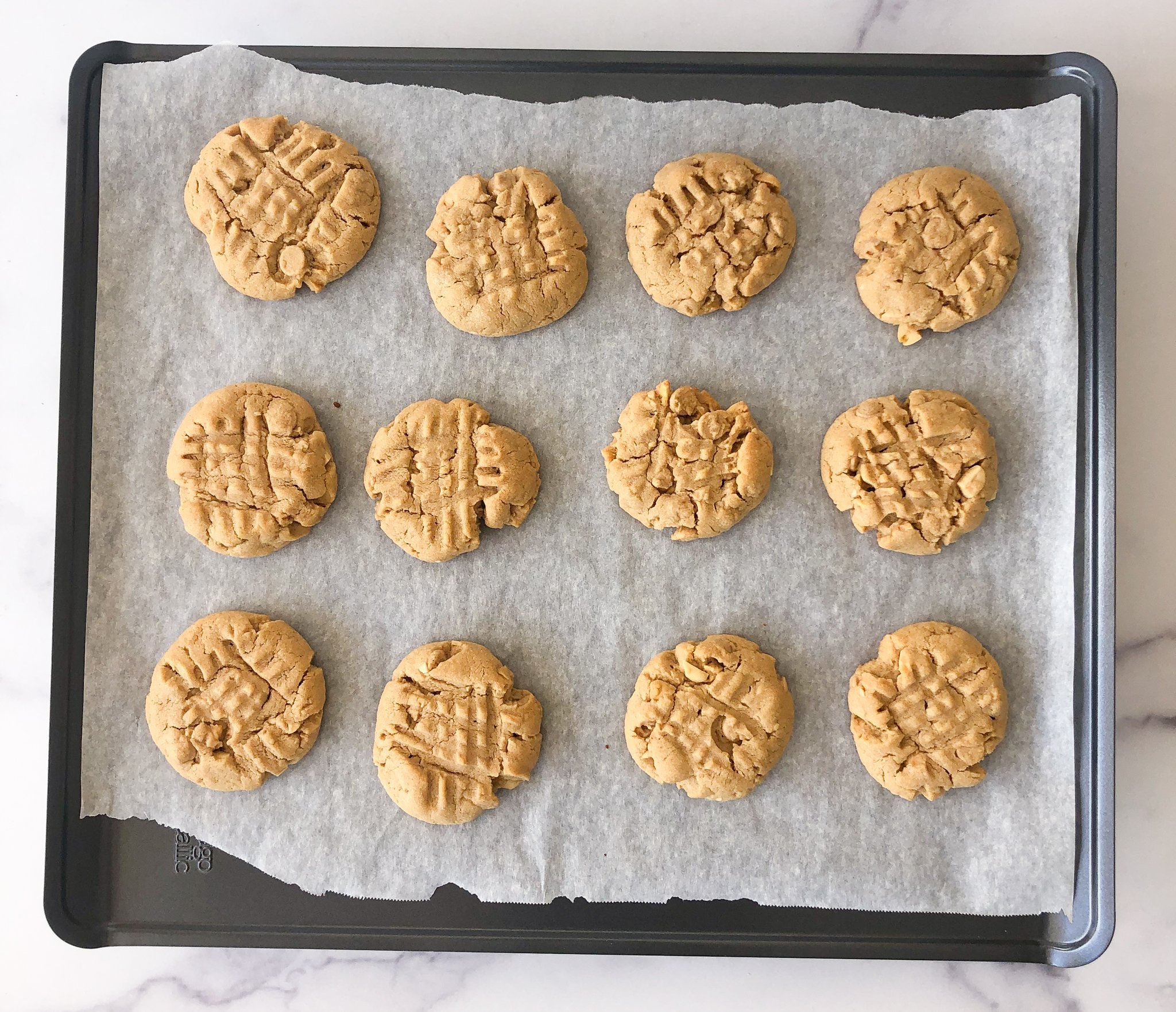 Baked peanut butter cookies on a parchment lined baking sheet.