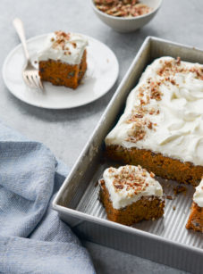 Classic carrot cake with cream cheese frosting in a baking dish and on a plate.