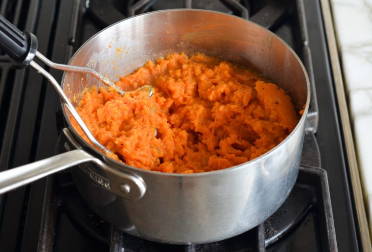 mashing the sweet potatoes in the butter mixture