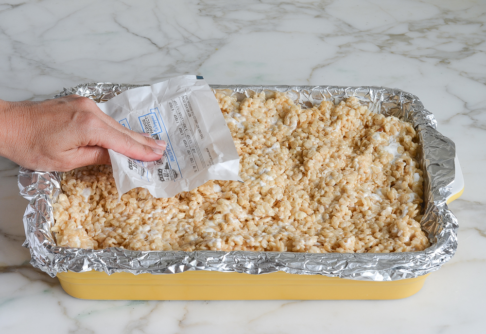 pressing rice krispie treat mixture into an even layer