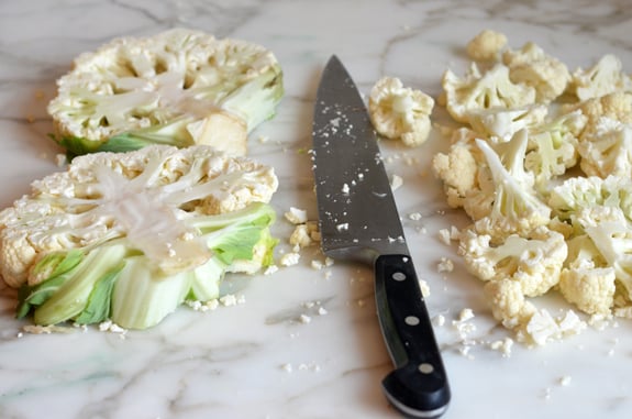Knife with cauliflower cut into steaks and florets.