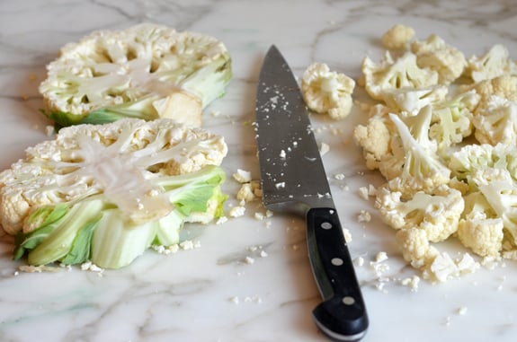 Knife with cauliflower cut into steaks and florets.