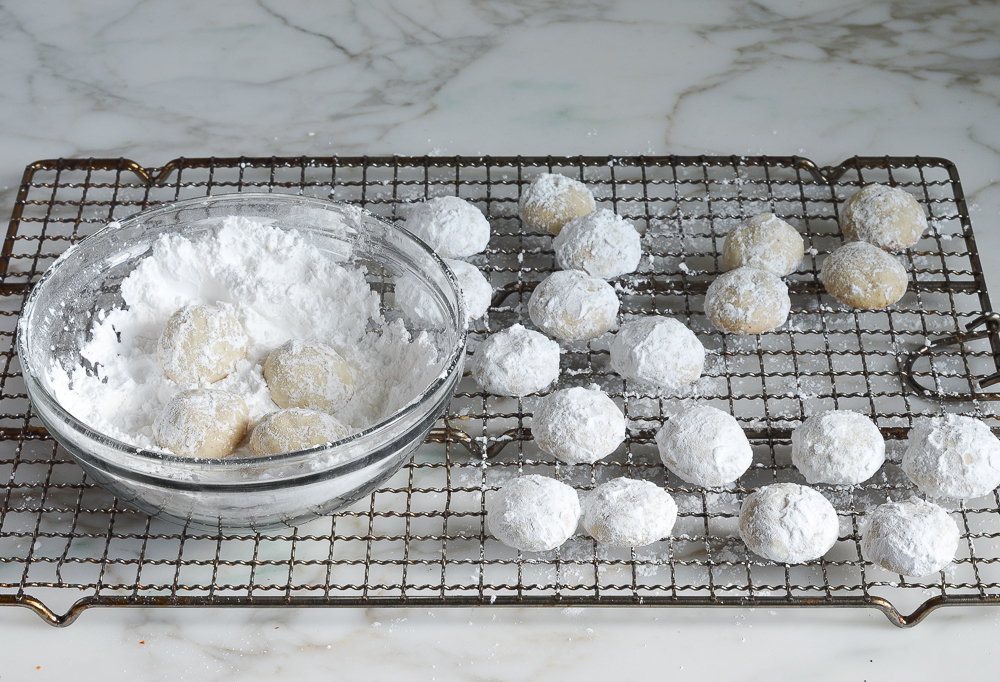 rolling Mexican wedding cookies again in confectioners sugar