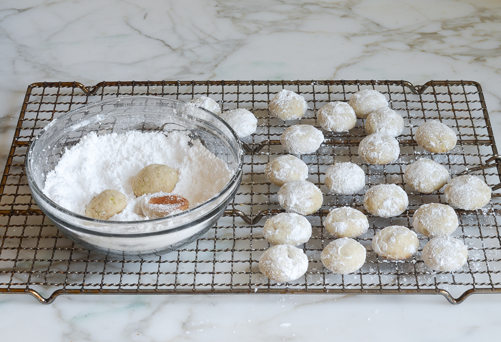 rolling Mexican wedding cookies in confectioners sugar