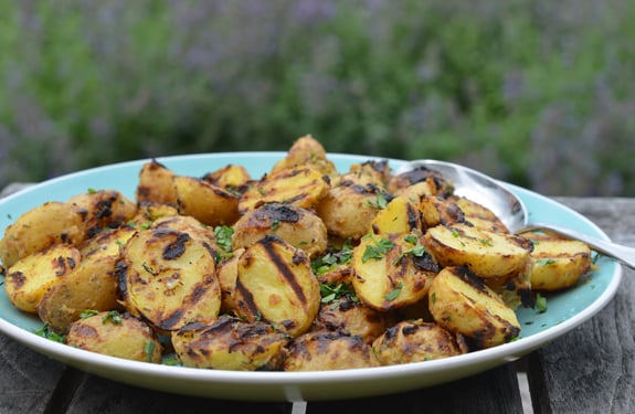 Plate of grilled baby potatoes with Dijon mustard and herbs.