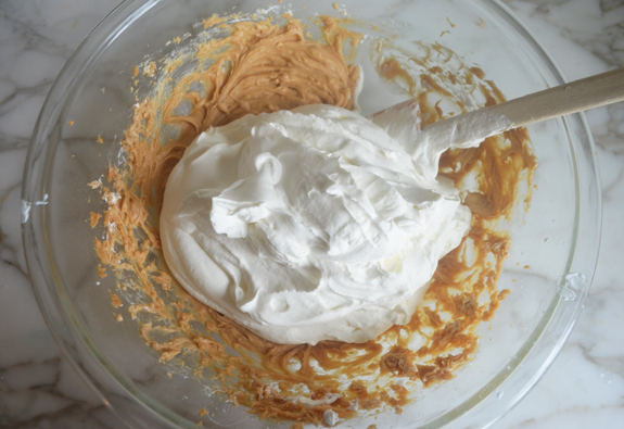 Large pile of whipped cream in a bowl with a peanut butter mixture.
