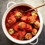 Spoon grabbing a meatball from a dish.