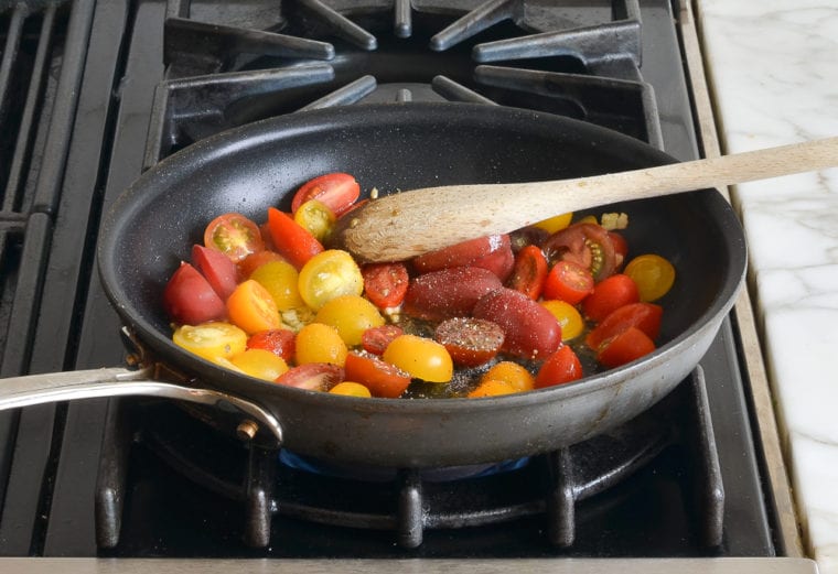 adding cherry tomatoes to the skillet