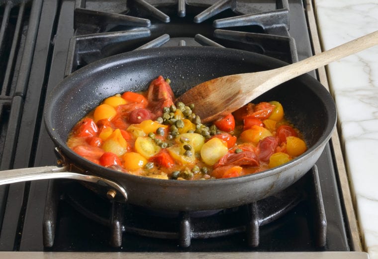 burst cherry tomatoes and capers in skillet