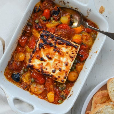 Baking dish of broiled feta with garlicky tomatoes and capers.
