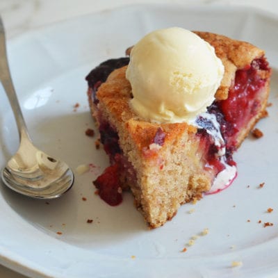 Piece of plum cake on a plate with a spoon.