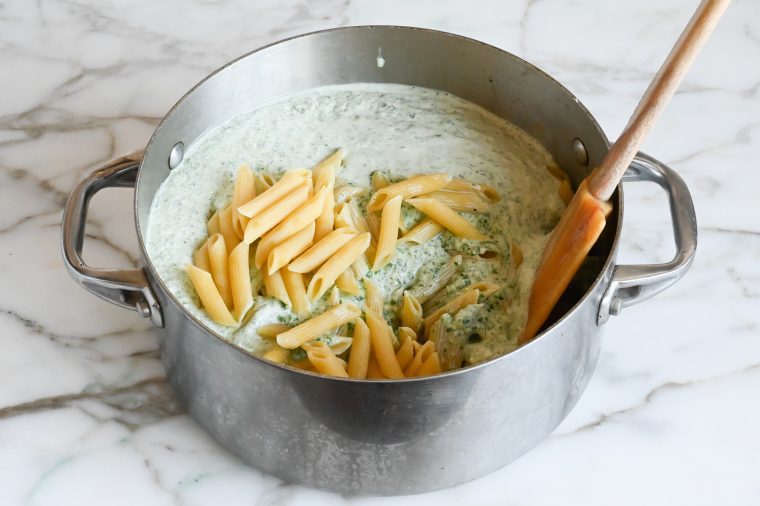 adding the spinach sauce to the pasta