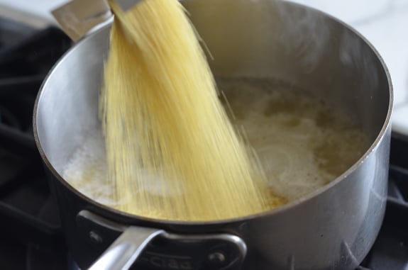 Couscous pouring into a pot of boiling broth.