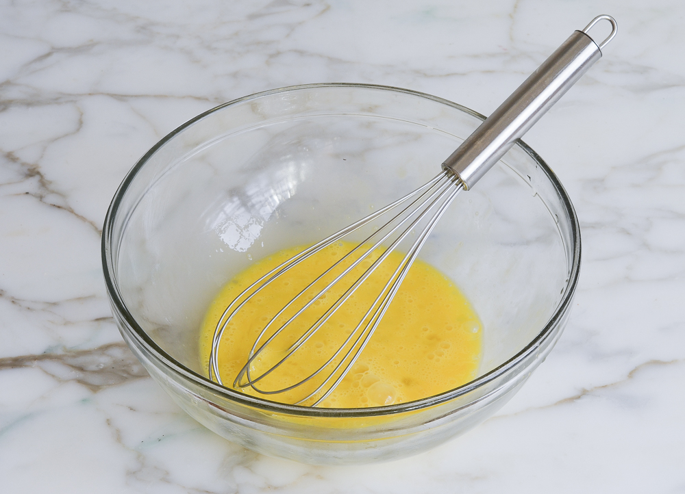 Glass bowl of whisked eggs.