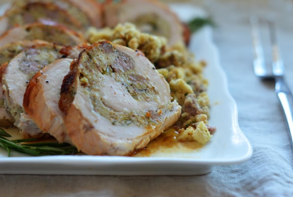 Slice of rolled turkey bread with sausage and herb stuffing on a plate.