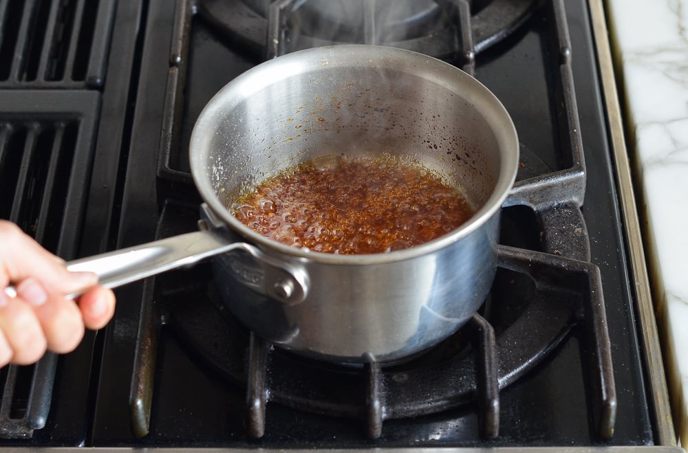 Bubbling caramel after adding water to saucepan on the stove.