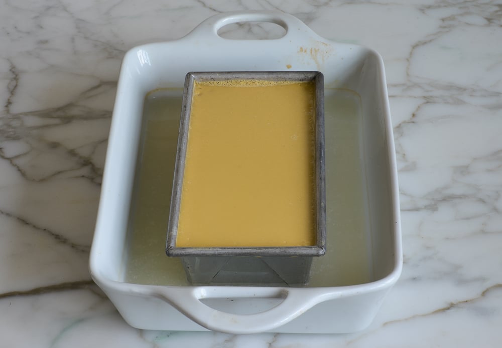 Baked flan cooling in water bath.