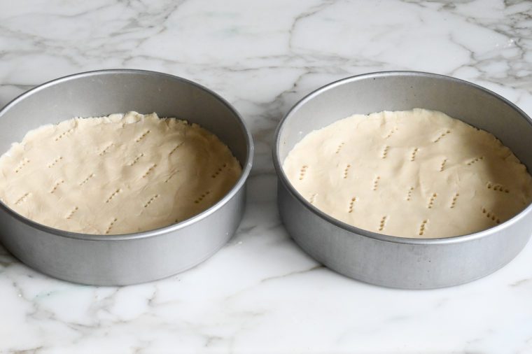 shortbread dough pressed into cake pans and ready to bake