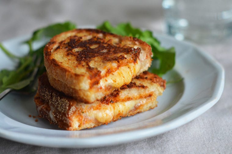 Two grilled cheese sandwich halves on a plate.