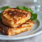 Halved grilled cheese sandwich stacked on a plate.