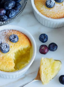 Lemon pudding cakes topped with powdered sugar and blueberries.