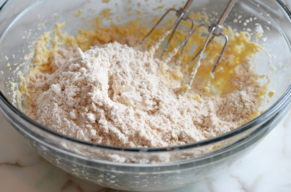 Dry ingredients added to a bowl of butter mixture.
