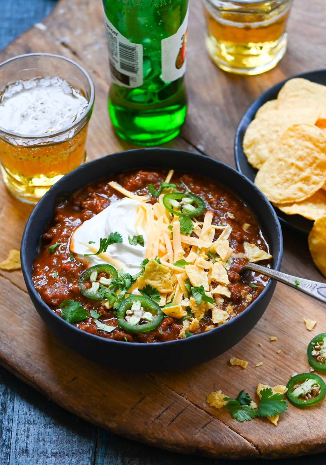 Chili in bowl with beer and tortilla chips.