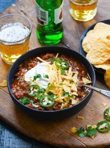 Chili in bowl with beer and tortilla chips.