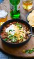 Chili in bowl with beer and tortilla chips.