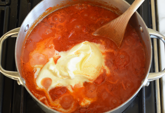 Creme fraiche melting into a pan of crushed tomatoes.