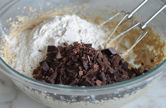 adding flour and chocolate chunks to the mixing bowl
